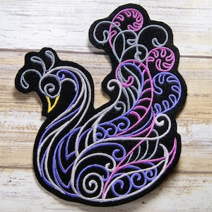 Peut inclure: Patch brodé noir représentant un paon stylisé avec des détails violets, roses et gris.