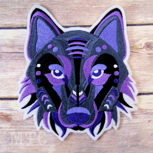 May include: Purple and black embroidered wolf head patch with a white border. The wolf's eyes are blue and the design is geometric.
