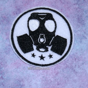 May include: Black and white embroidered patch of a gas mask with three stars. The gas mask is in the center of a white circle with a black outline.