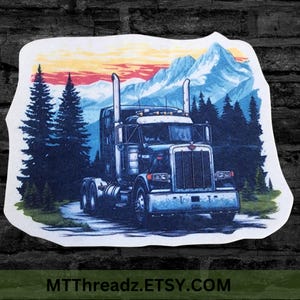 May include: A sticker featuring a dark semi-truck driving on a road through a forest with tall pine trees and snow-capped mountains in the background under a sunset sky. The text MTTREADZ.ETSY.COM is printed at the bottom of the sticker design.