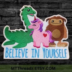 May include: Embroidered patch featuring a green dinosaur, a pink unicorn, and a brown monster with the text "Believe in Yourself".