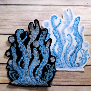 May include: Two embroidered patches depicting a blue and white stylized sea plant with a beaded stem. The patch on the left is on a black background and the patch on the right is on a white background.