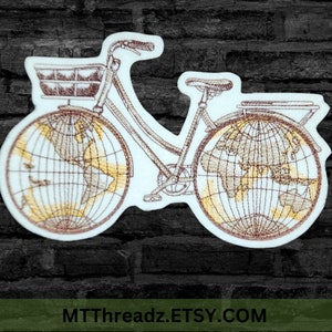 May include: Embroidered patch of a bicycle with globe wheels. The bicycle has a basket on the front and a rack on the back. The globes are brown and yellow with a grid pattern.