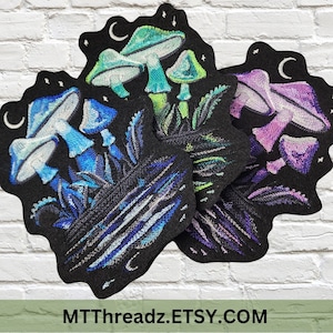 May include: Three embroidered felt patches featuring a group of mushrooms with a crescent moon and stars in the background. The patches are in shades of blue, green, and purple.