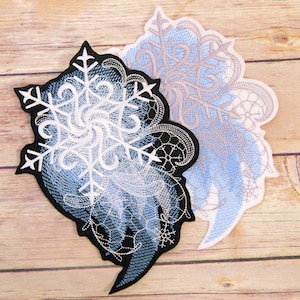 May include: Two embroidered snowflake patches, one with a black background and the other with a white background. Both patches feature a white snowflake design with blue and white swirls.