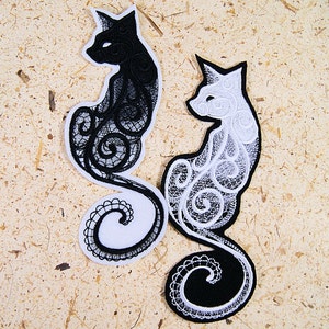May include: Two black and white embroidered cat patches with intricate swirling designs. The cats are facing to the right and have a curled tail.
