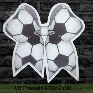 May include: A white and black soccer ball bow with a gray outline. The bow is in the shape of a butterfly. The text "MTThreadz.ETSY.COM" is at the bottom of the image.
