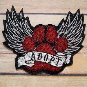 May include: Red embroidered paw print with wings and a banner that says "Adopt".