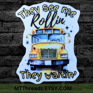 May include: A yellow school bus with the text "They see me rollin' They waitin'" and the website "MTTThreadz.ETSY.COM" printed on a white sticker.