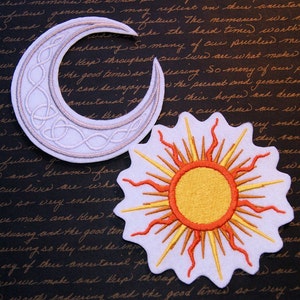 May include: Two embroidered patches, one a white crescent moon with a silver-colored Celtic knot design, and the other a white sun with orange and yellow rays.
