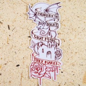 May include: An embroidered patch with a white background and red stitching. The patch features a bat with wings spread, a castle, a rose, and the text "Children of the Night What Music They Make!"