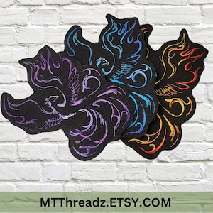 May include: Black, phoenix-shaped embroidered patches with colourful flame and bird designs. The patches feature purple, blue, and orange embroidery. The text "MTThreadz.Etsy.com" is at the bottom.