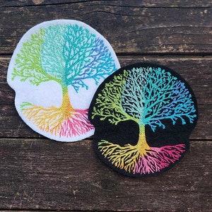 May include: Two embroidered patches featuring a colorful tree of life design. One patch is white with a rainbow tree and the other is black with a blue and green tree.