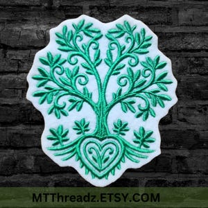 May include: A green embroidered patch of a stylized tree with a heart at the base. The tree has a thick trunk and many branches with leaves. The patch is on a white background.