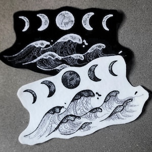 May include: Two black and white embroidered patches with a moon and wave design. The top patch has a black background with white embroidery. The bottom patch has a white background with black embroidery.