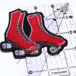 May include: Red roller skate patch with black and silver details. The patch is embroidered and has a vintage look.