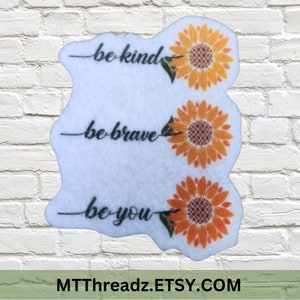 May include: Three white stickers with sunflower graphics and the text "be kind", "be brave", and "be you".