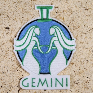May include: White embroidered Gemini zodiac sign patch with a blue background and green outline. The patch features the Roman numeral II and the word "GEMINI" in green.