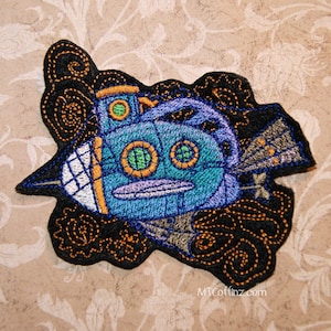 May include: Embroidered patch of a blue steampunk submarine with gold accents and green portholes. The submarine is surrounded by black and gold swirls.