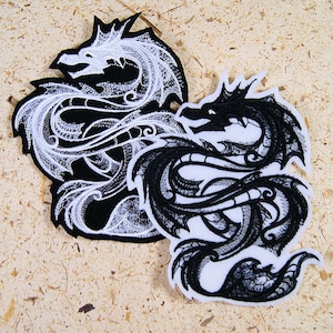 May include: Two embroidered iron-on patches featuring a black and white dragon design. The patches are in a yin-yang style, with one dragon in black and the other in white.