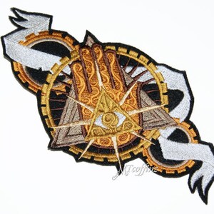 May include: An embroidered patch featuring a gold and brown design. The design incorporates a hand with an eye at its centre, encircled by a ring of gears and a banner.