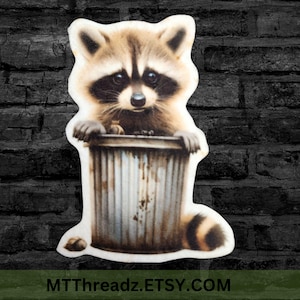 May include: A raccoon with a black mask and brown fur is peeking over the edge of a metal trash can. The raccoon's tail is wrapped around the can.