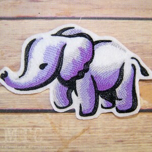 May include: Purple and white embroidered iron-on patch of an elephant. The elephant is outlined in black thread.