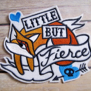 May include: Embroidered iron-on patch featuring a cartoon fox with the text "Little but Fierce" in a banner. The patch is white with orange, black, and blue accents.