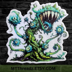 May include: A green and blue monster plant with multiple eyes and a large open mouth with sharp teeth. The plant has a white background and the text "MTTThreadz.ETSY.COM" at the bottom.