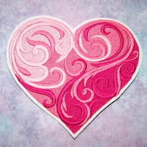 May include: A pink and white embroidered heart-shaped patch with a swirling design.