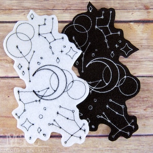 May include: Two felt patches with black embroidery of constellations, moons, and stars. One patch is white and the other is black.