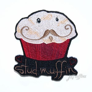 May include: Iron-on patch featuring an embroidered cartoon cupcake with a moustache and the text "stud muffin".