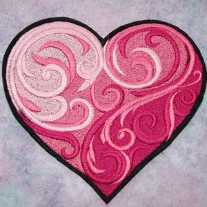 May include: A pink and red embroidered heart-shaped patch with a swirling design. The patch has a black outline.