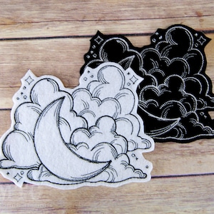 May include: Two embroidered patches, one white and one black, featuring a crescent moon in a cloud. Both patches have a detailed, hand-drawn style.