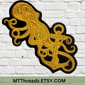 May include: A gold embroidered patch of an octopus wrapped around an anchor. The patch is on a black background.