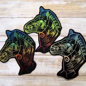 May include: Three black felt patches with embroidered images of zebra heads in a rainbow color scheme.