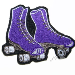 May include: Purple roller skate patch with black stitching and white wheels. The patch is embroidered with a detailed design of the skates.