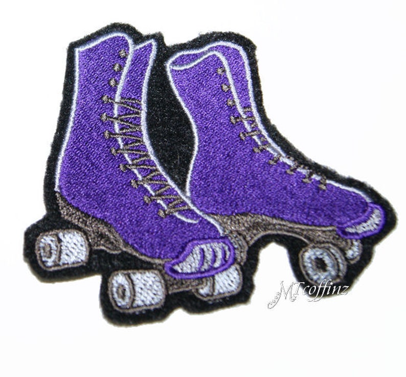 May include: Purple roller skate patch with black stitching and white wheels. The patch is embroidered with a detailed design of the skates.