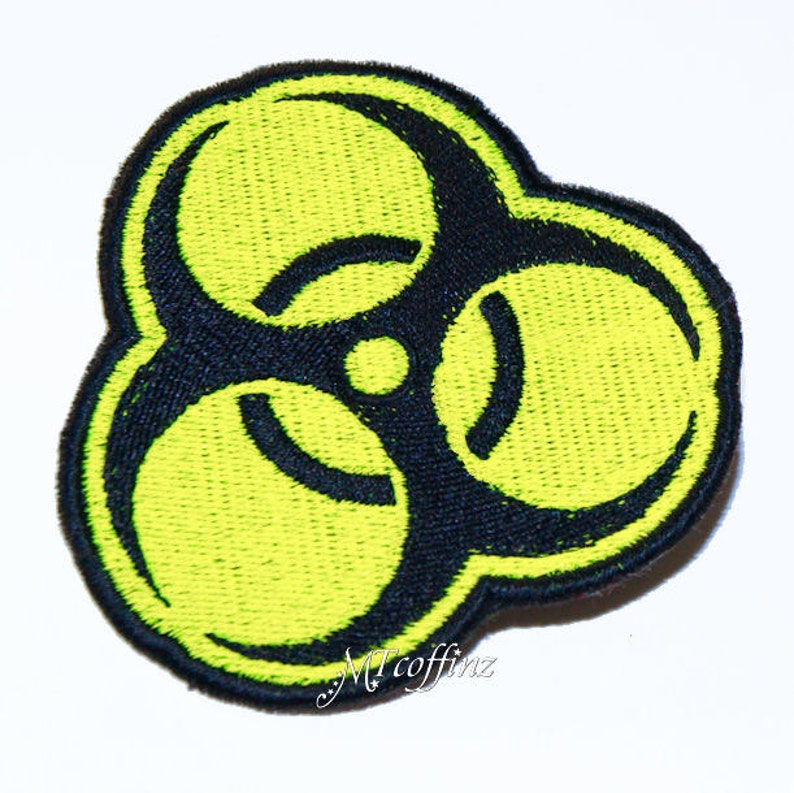 May include: A yellow biohazard symbol patch with black outlines. The patch is made of embroidered fabric.