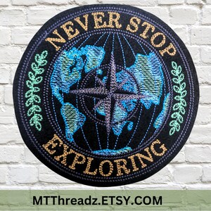 May include: Embroidered patch with a black background, a blue and green globe with a compass, and the text "NEVER STOP EXPLORING" in gold lettering.