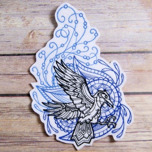 May include: Embroidered patch featuring a black and white raven with intricate blue and white floral designs. The raven is in flight with its wings spread wide.