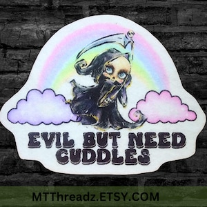May include: A die-cut sticker featuring a cartoon Grim Reaper character with blue eyes, a black cloak, and a scythe, set against a rainbow and clouds. The text "EVIL BUT NEED CUDDLES" is displayed below the character.