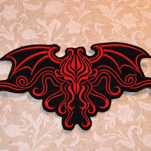 May include: Black and red embroidered patch featuring a stylized Cthulhu with wings. The patch is made of felt and has a red outline.