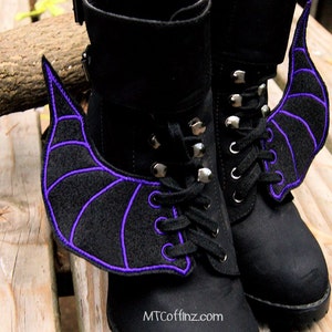 May include: Black boots with purple bat wings attached to the sides. The wings are made of felt and have a purple embroidered outline.