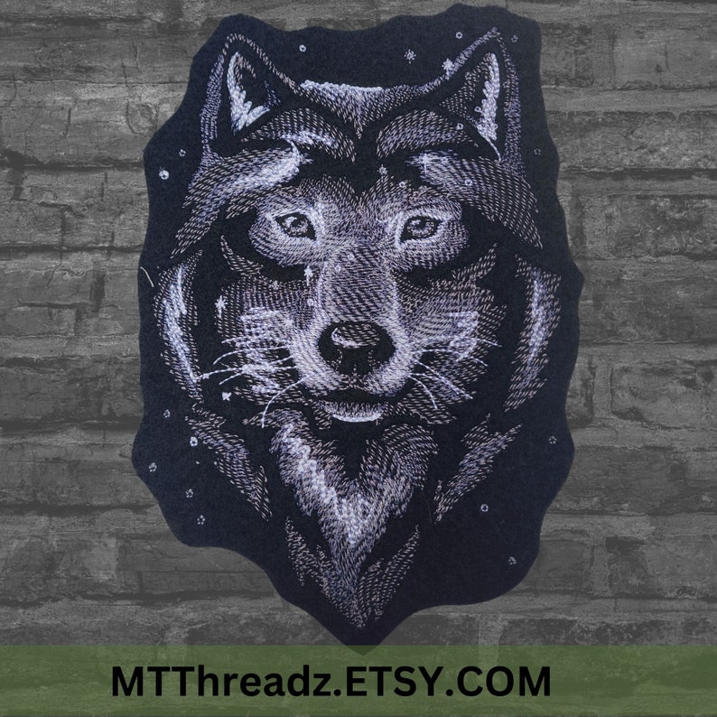 K&ouml;nnte beinhalten: Gestickter Aufn&auml;her mit dem Gesicht eines Wolfes vor einem sternenklaren Nachthimmel. Der Wolf ist wei&szlig; und der Hintergrund ist schwarz. Der Aufn&auml;her ist aus Filz und hat einen Durchmesser von etwa 10 cm.