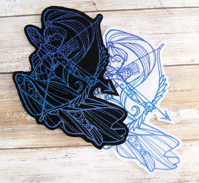 May include: Two embroidered patches of a female archer with a bow and arrow. One patch is black with blue embroidery, the other is white with blue embroidery.