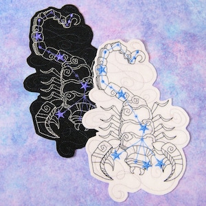 May include: Two embroidered patches depicting the constellation Scorpio, one in black and one in white. Both patches feature a scorpion with a detailed outline and blue stars representing the constellation.