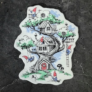 Peut inclure: Un design brodé fantaisiste d'une maison dans les arbres à plusieurs niveaux, avec des gnomes qui grimpent aux échelles et se balancent sur une corde. La maison dans les arbres a une porte rouge et des fenêtres, et l'arbre est décoré de feuilles vertes et de ciel bleu.