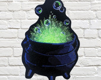 May include: A black cauldron with green bubbling liquid and blue accents. The cauldron is on a white brick background.  MTTThreadz.ETSY.COM