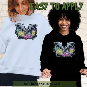 May include: White and black hoodies with an embroidered bat and flower design. The design features yellow, pink, and green floral accents. The text "EASY TO APPLY" is above the hoodies. The Etsy shop name is displayed at the bottom of the image.